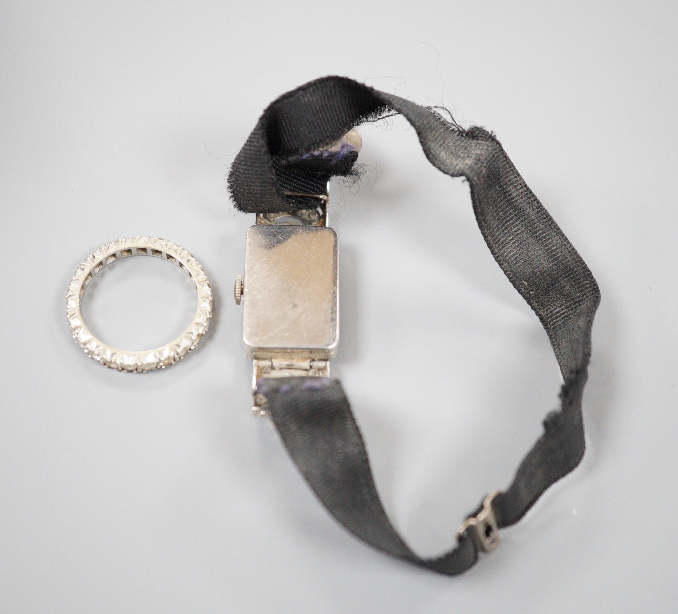 A lady's white metal (stamped all platinum) and diamond set manual wind cocktail watch, gross weight 13.2 grams and a 9ct white metal and synthetic white spinel set full eternity ring.